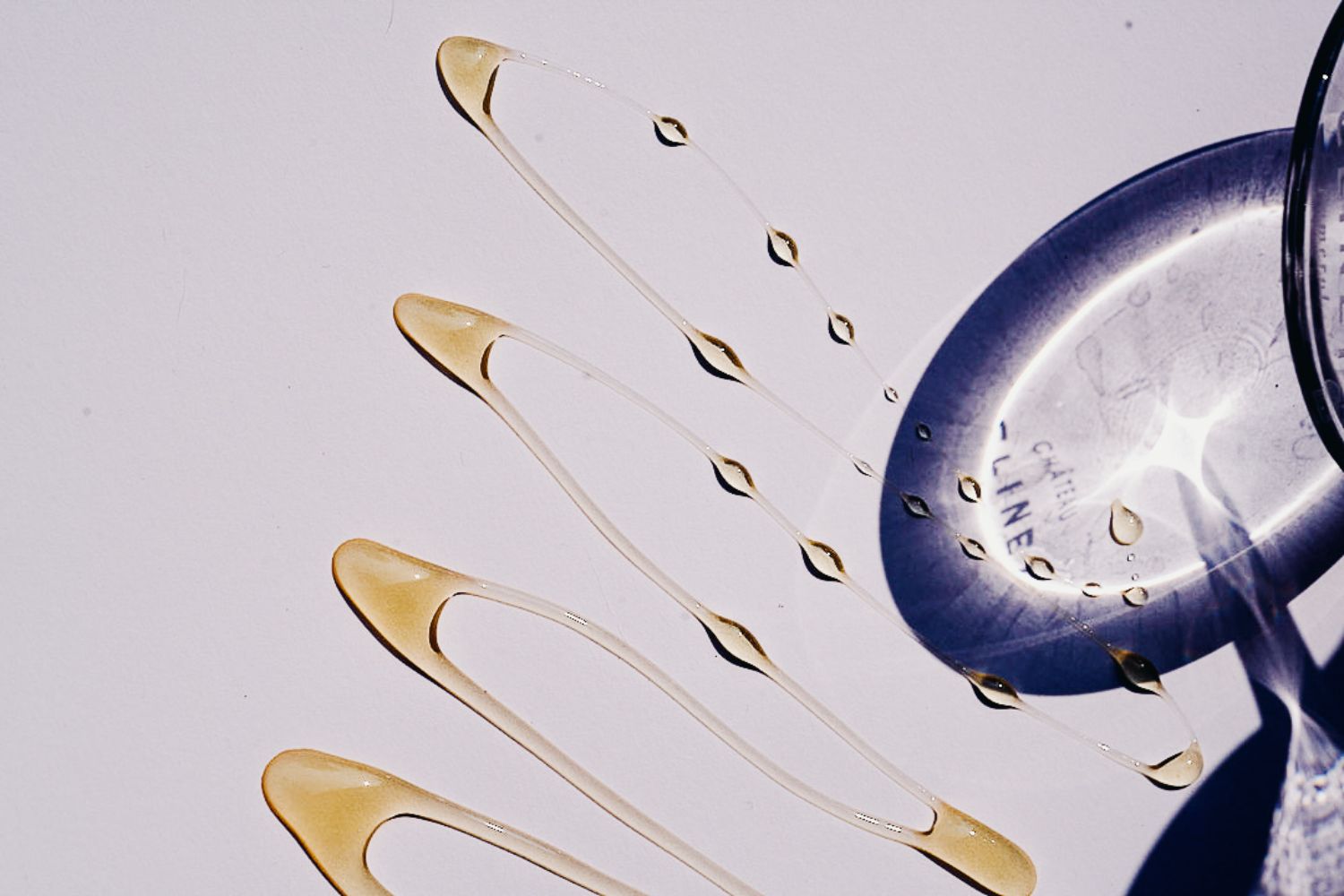 Shadow of a Clinet wine glass stem, next to a zigzag of honey textures.